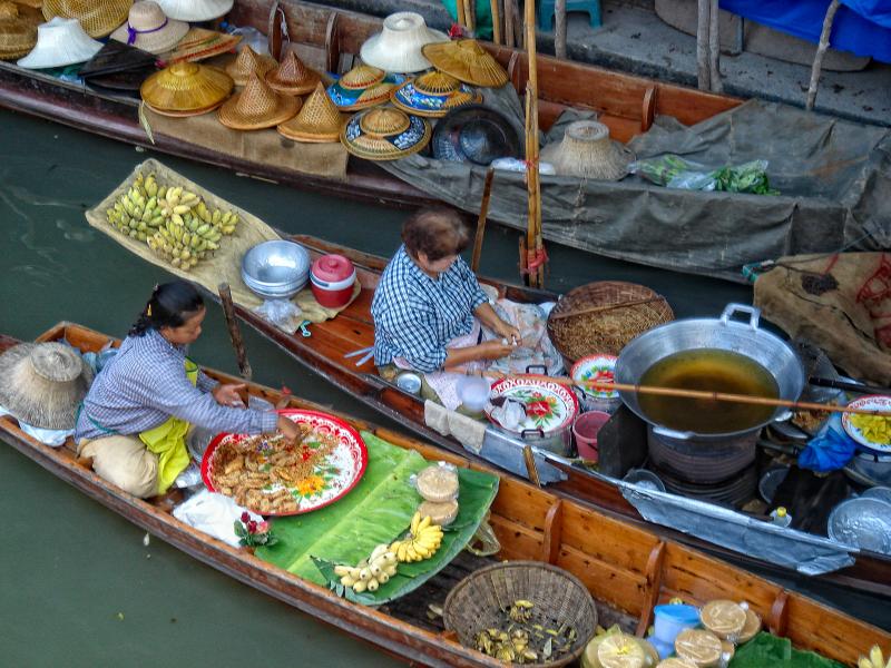 Women prepare food for sale at floating market, Thailand