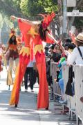 A stilt-walker dressed as Fire high-fives an onlooker in San Francisco's Carnaval parade.