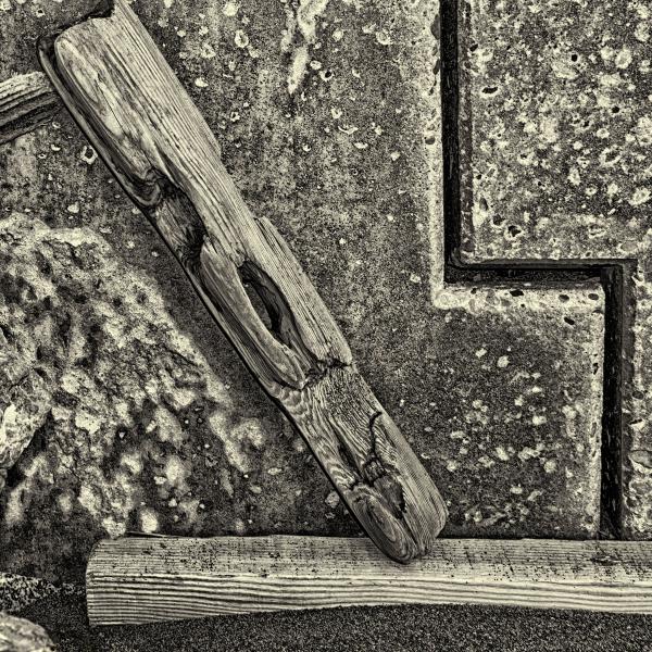 Driftwood and buried plank at base of Pacifica Seawall