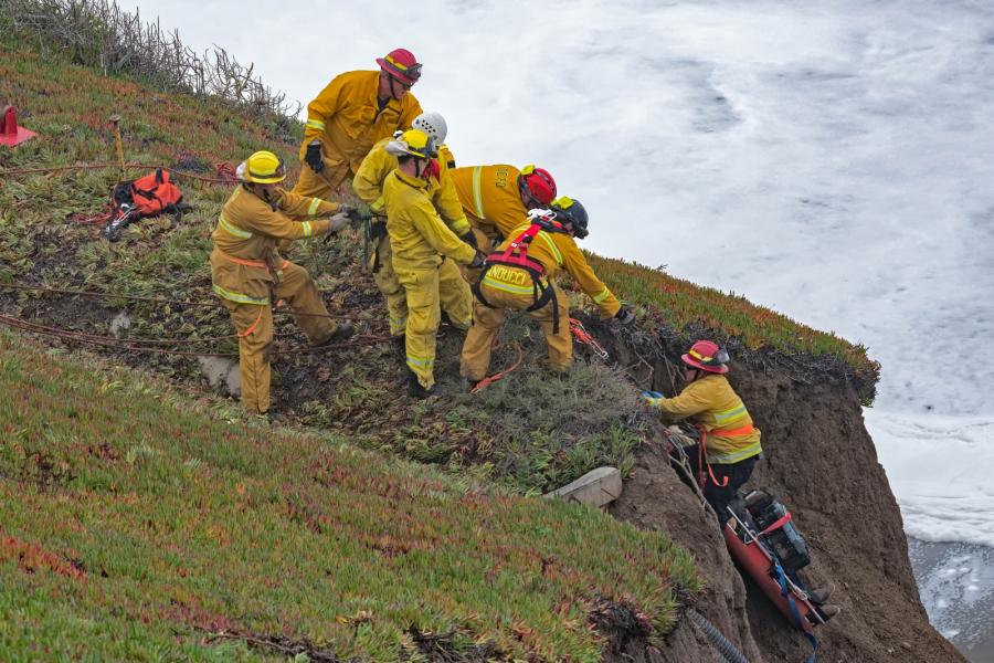 Firefighters recover the body of a hang-glider accident victim on the Pacifica coast