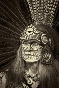 Man with face painted for Dia de Los Muertos and wearing ceremonial Aztec feather headress.