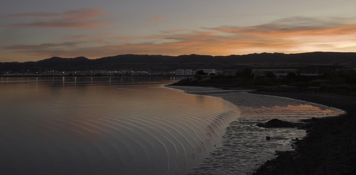 Advancing tide under a colored sky.