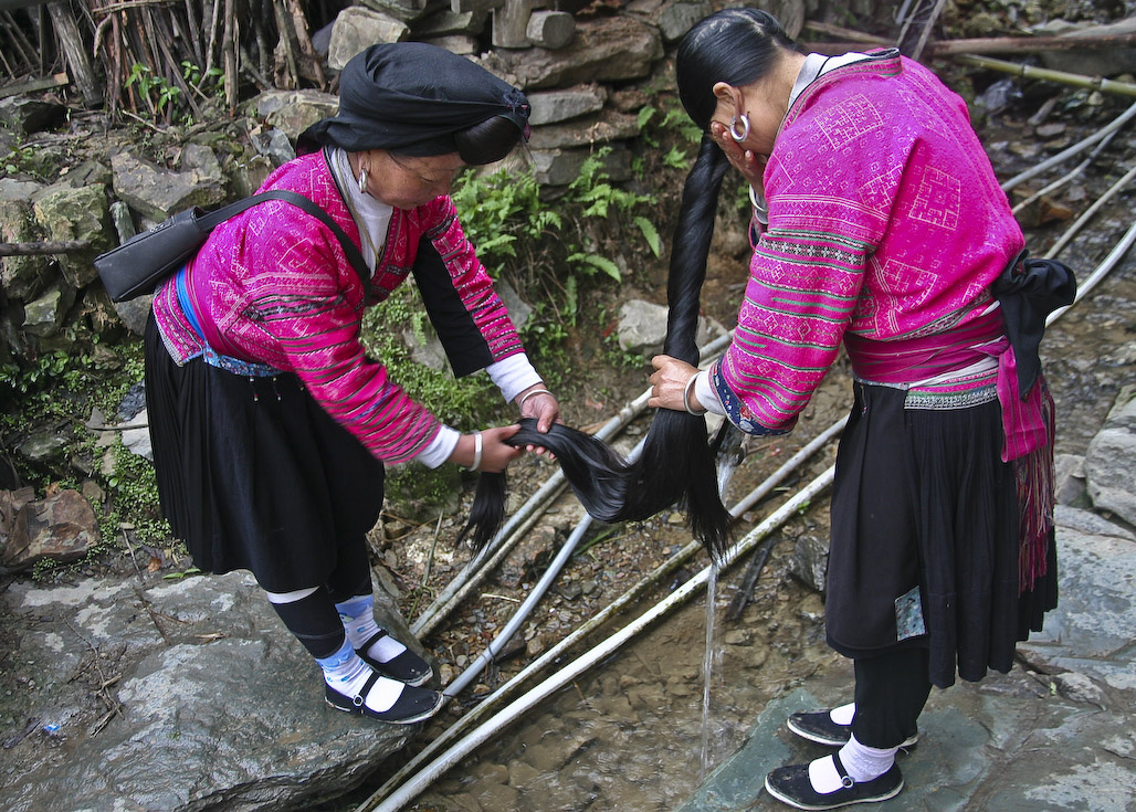 Zhuang minority woman helping her peer to wash her hair, Guangxi, China