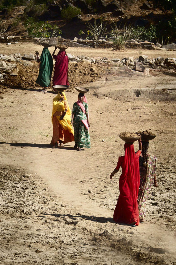 Beautiful ladies transporting dirt in the field,India