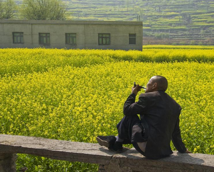 Man smoking his pipe, basking under the sun, Guangxi, China