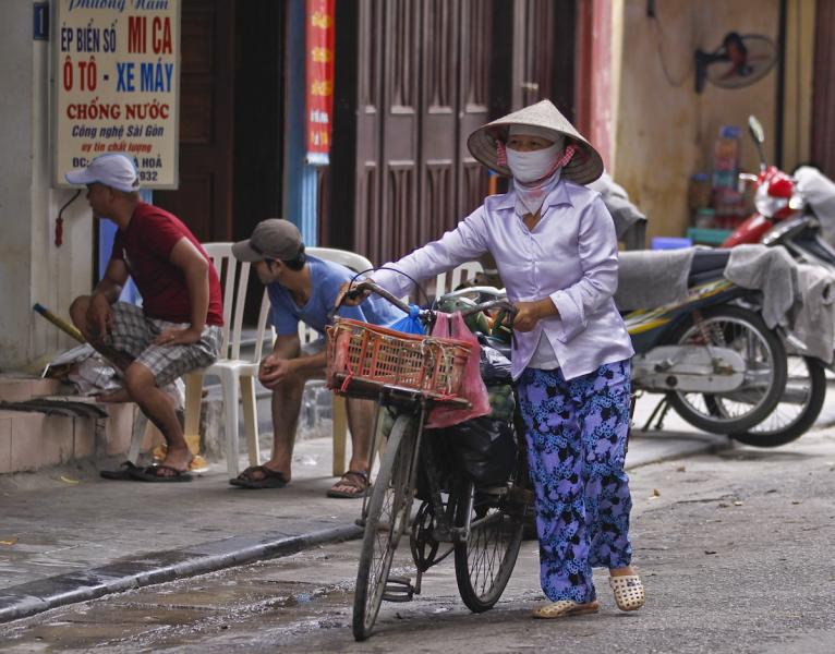 A Local Merchant transporting her goods on a bike, Hanoi, Vietnam