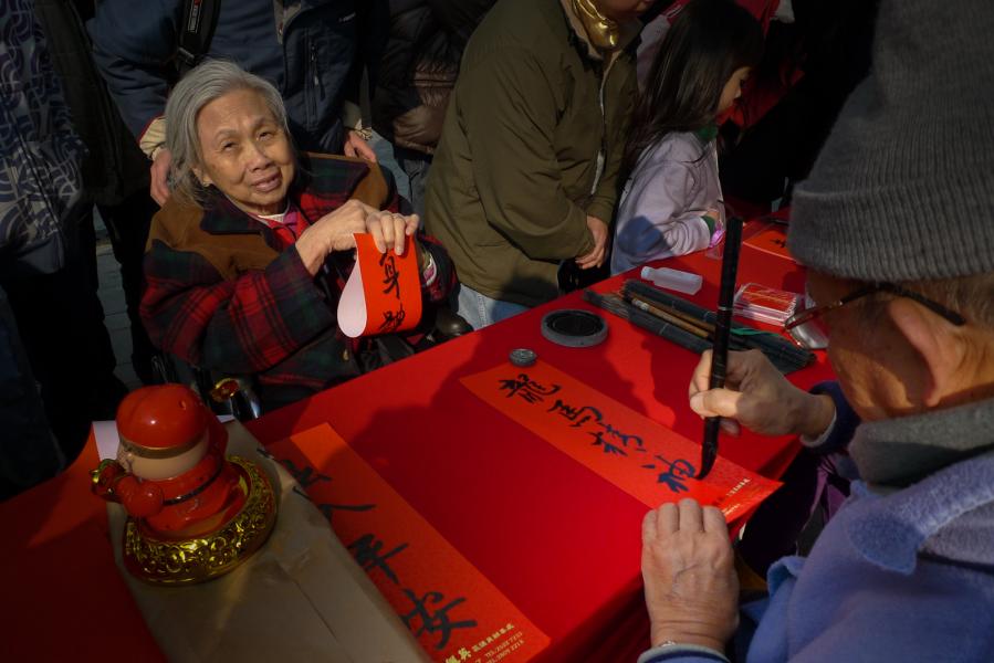 Elderly woman receiving Chinese Near Year lucky messages from Lions Club member, Stanley Market, Hon